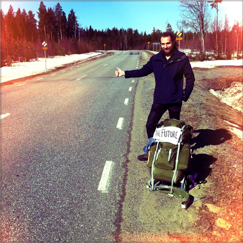 A guy with a backpack asking for a lift on the side of the road